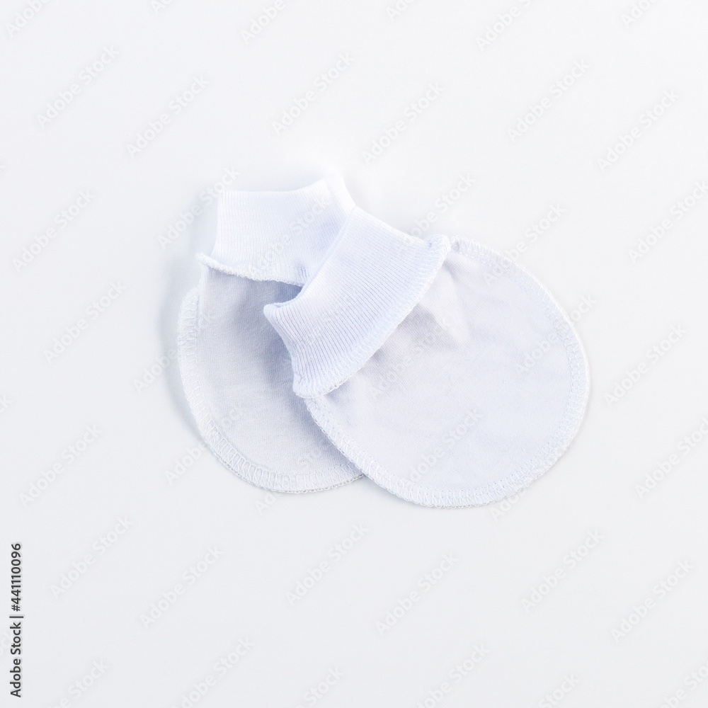 White mittens for newborns, top view. We're expecting a baby. It's time to give birth, it's time to go to the maternity hospital. Concept: fashion for newborns, a variety of colorful clothes. White mittens for newborns, top view. We're expecting a baby. It's time to give birth, it's time to go to the maternity hospital. Concept: fashion for newborns, a variety of colorful clothes.