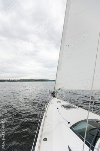 River boat trip. Details on a sailing yacht. We go by boat in the summer. White yacht with full sails running downwind wing-on-wing, sailing after the storm. Leisure activity, sport, recreation theme. © Anna