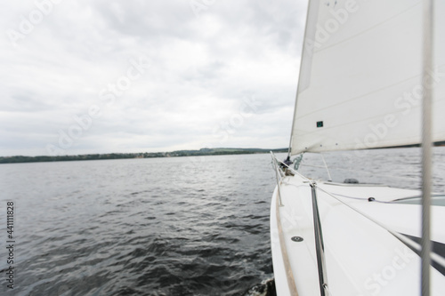 River boat trip. Details on a sailing yacht. We go by boat in the summer. White yacht with full sails running downwind wing-on-wing, sailing after the storm. Leisure activity, sport, recreation theme.