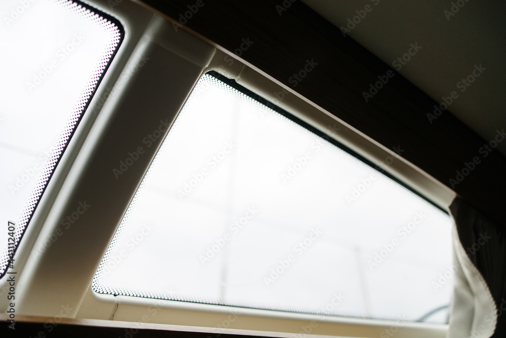 Obraz premium Boat trip on the river. Details about the sailing yacht. In the summer we go by boat. A white yacht with full sails. Leisure, sports, recreation theme. Window from inside the cabin 
