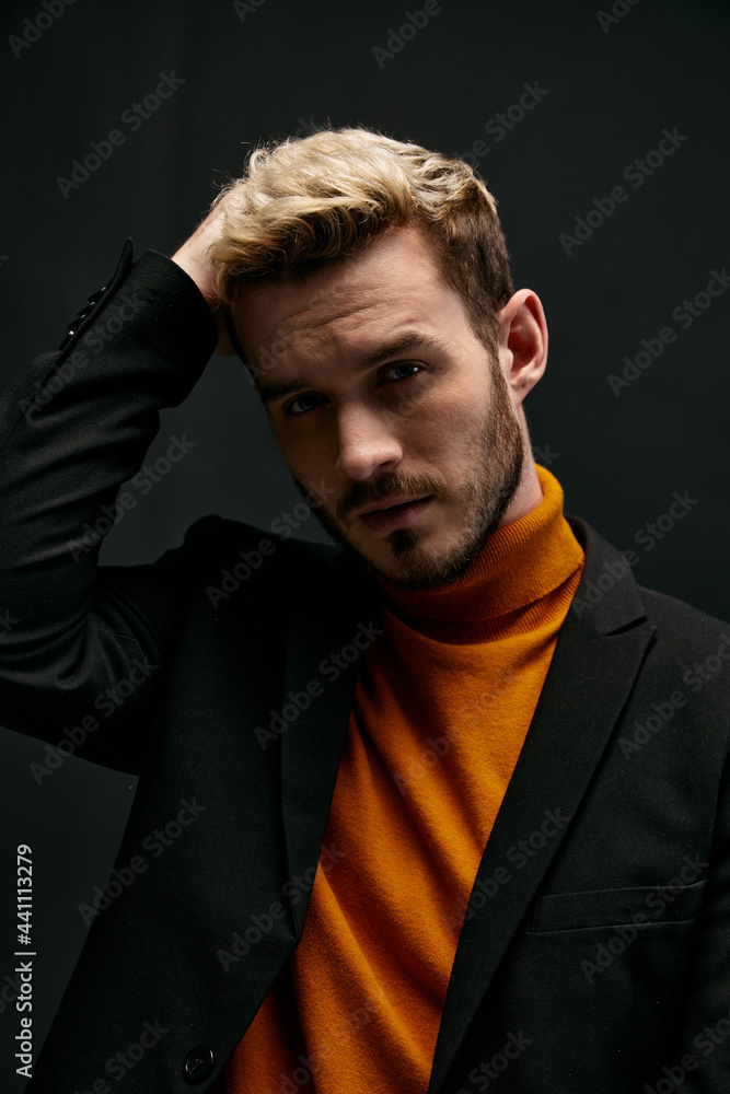portrait of handsome blond man in jacket orange sweater on dark background close-up cropped view portrait of handsome blond man in jacket orange sweater on dark background close-up cropped view