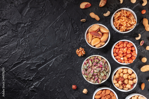 Nuts on a black background with a place for text, overhead flat lay shot of peanuts, walnuts etc