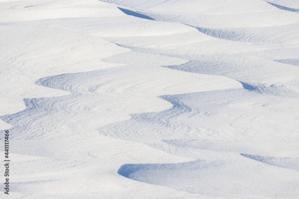 Beautiful winter background with snowy ground. Natural snow texture. Wind sculpted patterns on snow surface. Arctic, Polar region. Beautiful winter background with snowy ground. Natural snow texture. Wind sculpted patterns on snow surface. Arctic, Polar region.