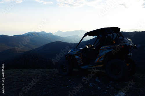 Buggy machine parked in mountains at sunset