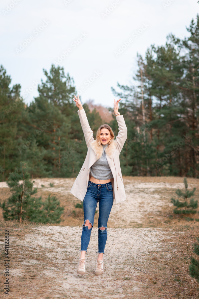 Obraz premium Young beautiful blonde long haired woman with raised hands over green natural forest background outdoor.