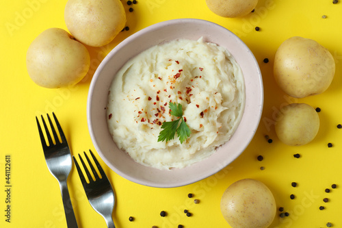 Plate of mashed potatoes and ingredients on yellow background
