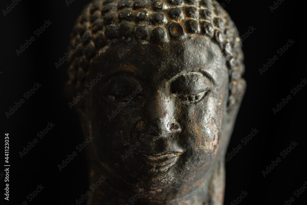 Close-up view of old buddha statue on black background Close-up view of old buddha statue on black background