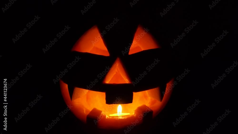 Close-up of Jack lantern. Scary face is carved into orange pumpkin. One candle burns inside the vegetable. Halloween night. Close-up of Jack lantern. Scary face is carved into orange pumpkin. One candle burns inside the vegetable. Halloween night.