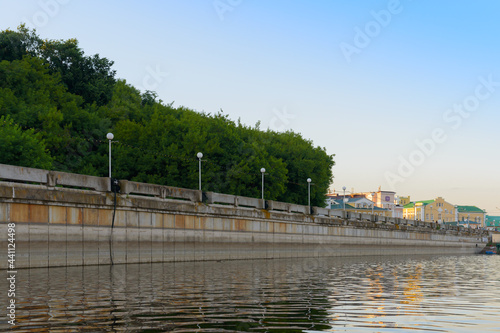 Concrete bank of an artificial reservoir with lanterns and forest