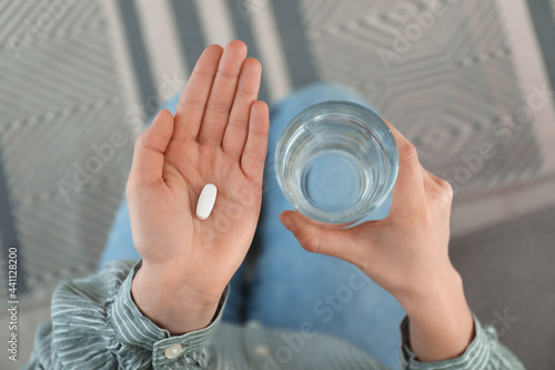 Young woman with abortion pill and glass of water, top view