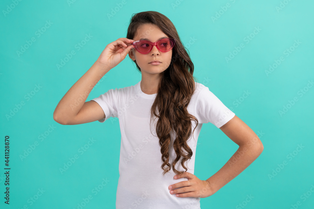 serious teen girl long curly hair in sunglasses casual style on blue background, summer style serious teen girl long curly hair in sunglasses casual style on blue background, summer style