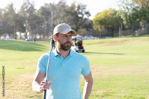 male golf player on professional golf course. portrait of golfer in cap with golf club.