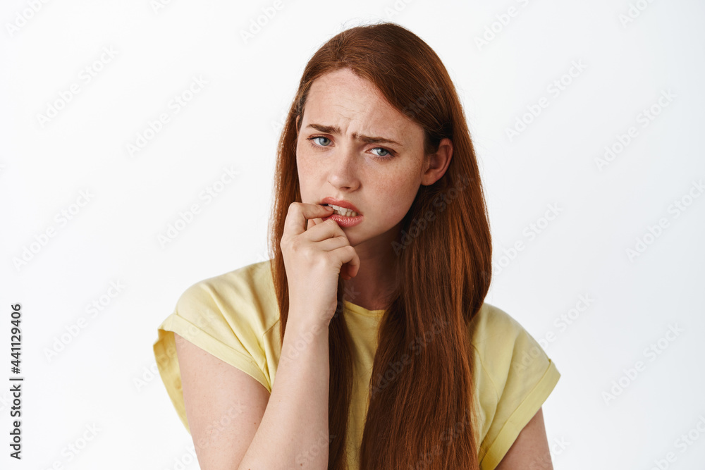 Hesitant redhead woman has doubts, touching lip and frowning concerned, looking at camera and pondering, thinking of something serious, white background Hesitant redhead woman has doubts, touching lip and frowning concerned, looking at camera and pondering, thinking of something serious, white background