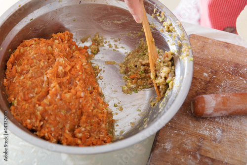 Digging dumpling stuffing with wooden spoon in hand