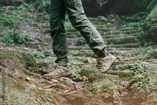 Unrecognizable woman dressed in trekking pants and shoes walks through the woods.