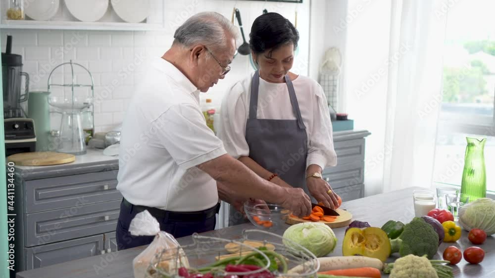 Senior Asian married couple cooking food at kitchen home. Elderly 70s man and woman preparing ingredients at kitchen counter together Senior Asian married couple cooking food at kitchen home. Elderly 70s man and woman preparing ingredients at kitchen counter together