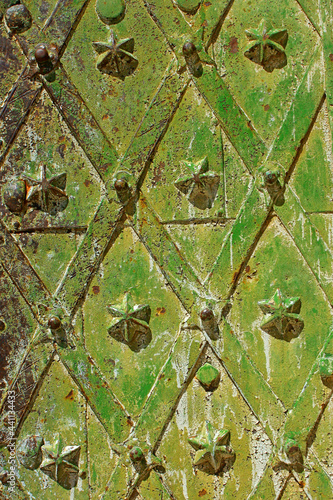 Fragment of an ancient wrought-iron medieval metal reliable door with decorative figures, painted in many layers mainly in shades of green