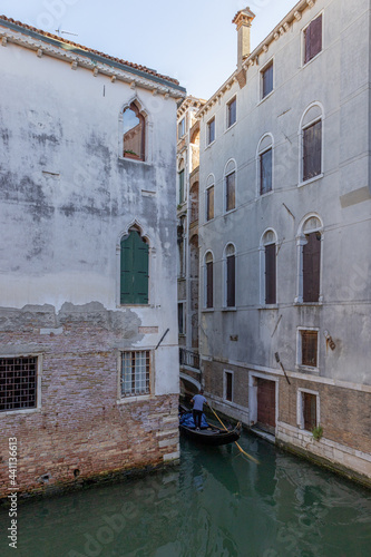 A gondola passing by a normal, unglamorous small canal in Venice, Italy. photo