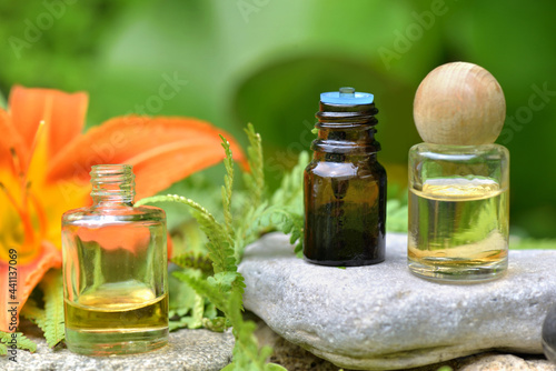 essential oil  bottles on a  stone in a rock zen garden  with orange flower