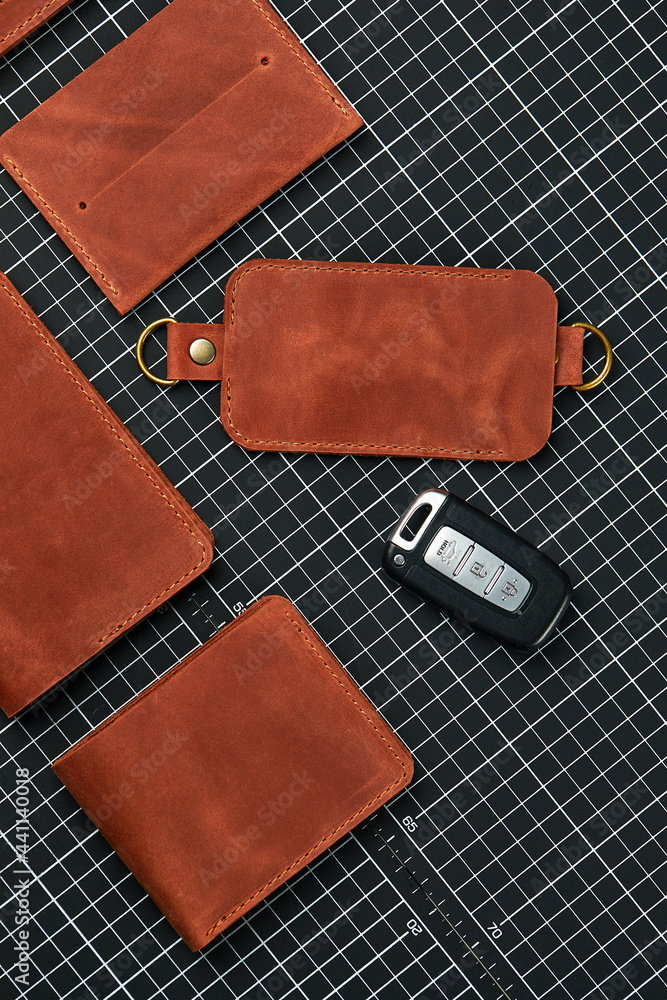 A set of wallets, business card holders and key holders made of handmade leather, made of red leather on a table for cutting leather, surrounded by tools, demonstration of handmade leather products A set of wallets, business card holders and key holders made of handmade leather, made of red leather on a table for cutting leather, surrounded by tools, demonstration of handmade leather products