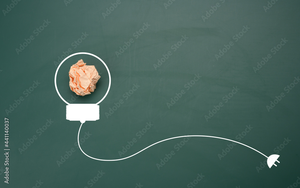 crumpled sheet of  paper on a green background, shape of a light bulb. Energy saving concept