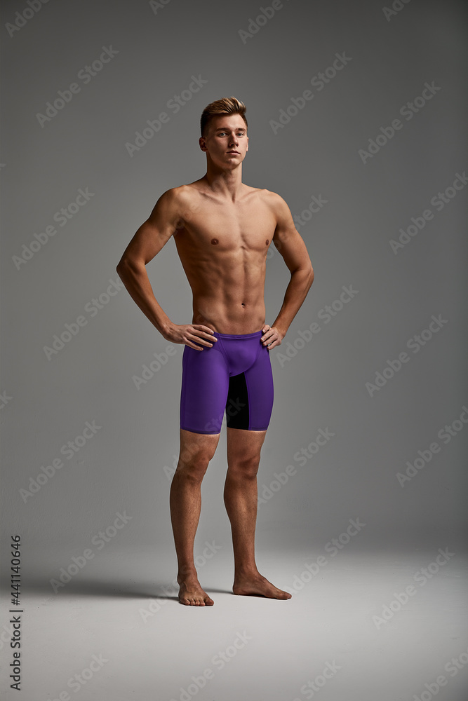 Young attractive swimmer in excellent physical shape isolated on gray background