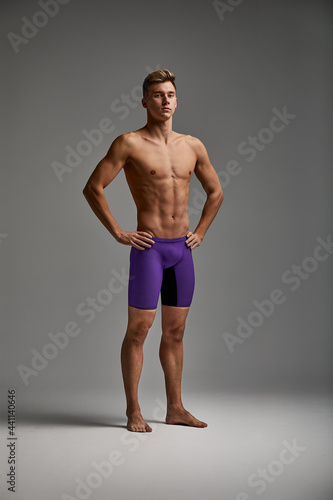 Young attractive swimmer in excellent physical shape isolated on gray background