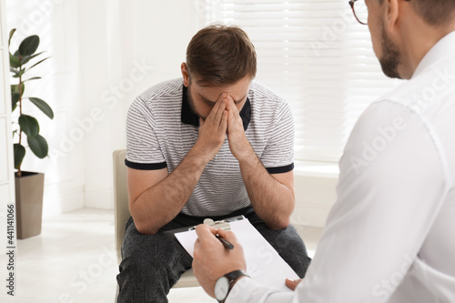 Psychotherapist working with drug addicted young man indoors photo