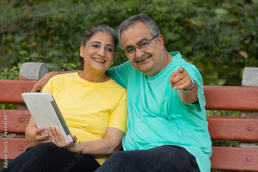 A HAPPY ADULT MAN POINTING AWAY WHILE SITTING WITH WIFE