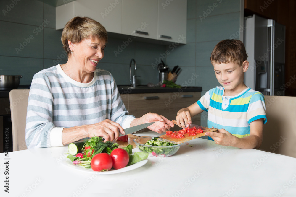 grandmother and grandson together make salad for lunch at home grandmother and grandson together make salad for lunch at home