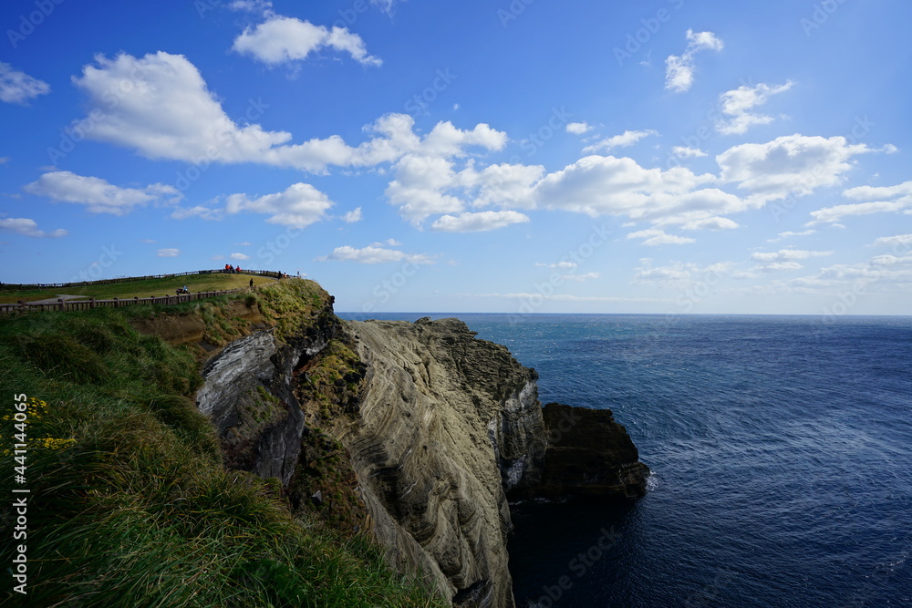 a beautiful seaside view with a cliff walkway, against charming clouds