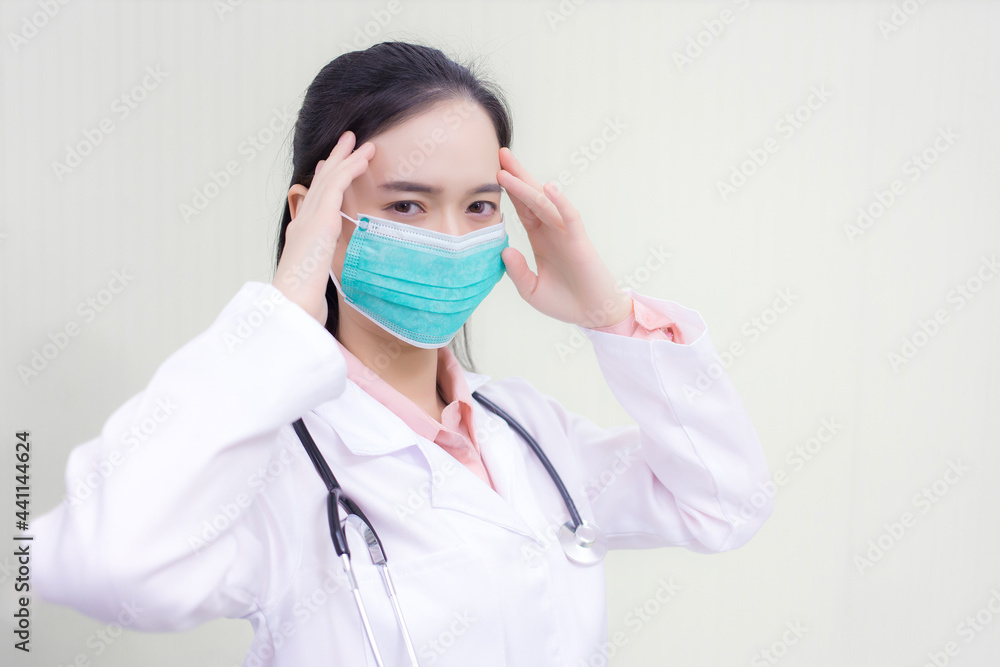 Asian female doctor Sitting in the examination room wearing a mask and pondering in  health care,pollution PM2.5,new normal and coronavirus protection concept.