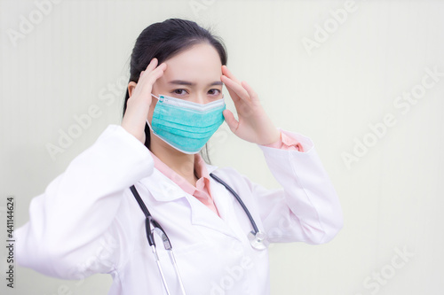 Asian female doctor Sitting in the examination room wearing a mask and pondering in  health care pollution PM2.5 new normal and coronavirus protection concept.