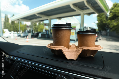 Photography Paper coffee cups on car dashboard at gas station. Space for text