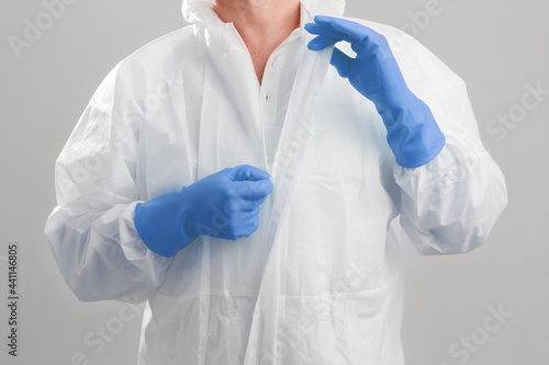 Close up shot the men in protective hazmat suit pull the zipper out after finish work at the hospital. macro shot men's hands unzips the PPE hazmat suit