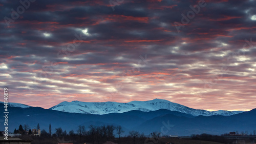 Beautiful colored sunset with mountain covered in snow in late Winter © Mihai