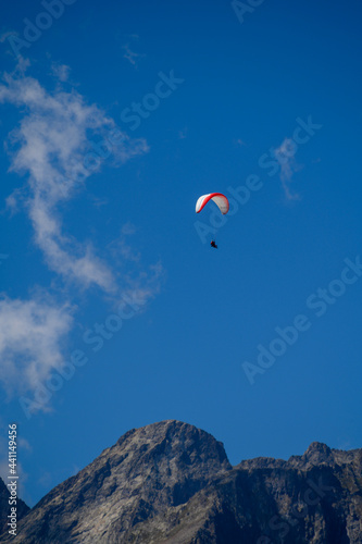 Paraplaners in tandem gliding in blue sky and Alpine mountains on paraplane