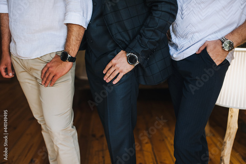 Several gentlemen, businessmen men stand in the office showing watches, holding their hands in their pockets. Working environment. Photography, concept.