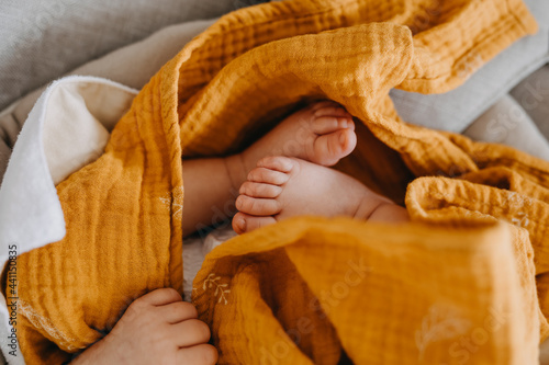 Closeup of newborn baby feet, covered with yellow blanket. photo