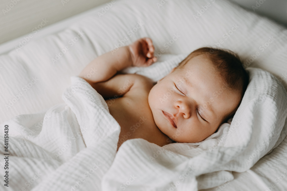 Newborn baby sleeping in a baby nest, covered with white blanket. Newborn baby sleeping in a baby nest, covered with white blanket.