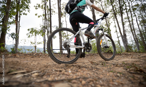 Woman cycling on mountain top forest trail