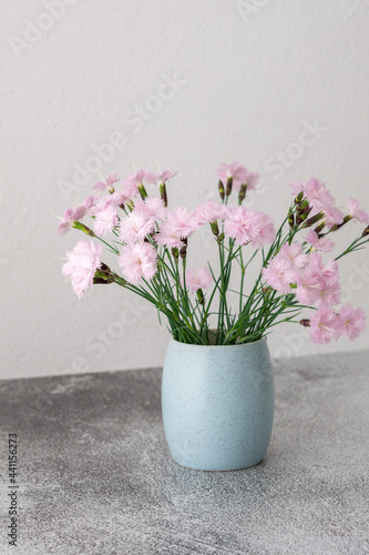 Wallpaper Mural Small pink carnations in a mug on a white wall background, part of a home interior Torontodigital.ca