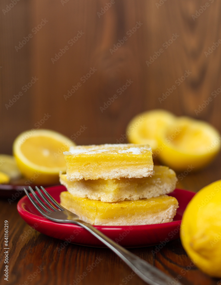 side view of juicy yellow lemon cakes on wooden background, stack of citrus cookies with lemon filling lying one on top of another
