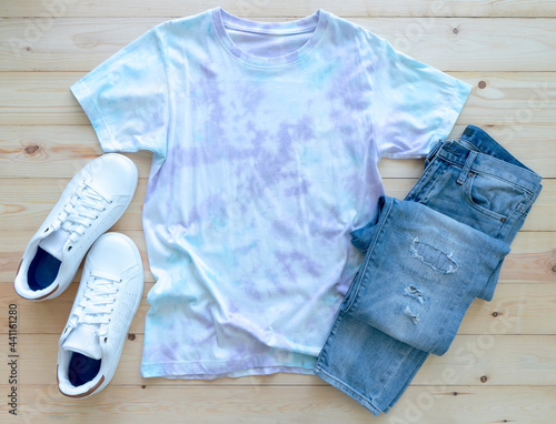Colorful tie die tshirt, jean and shoes on wooden background. fashion summer