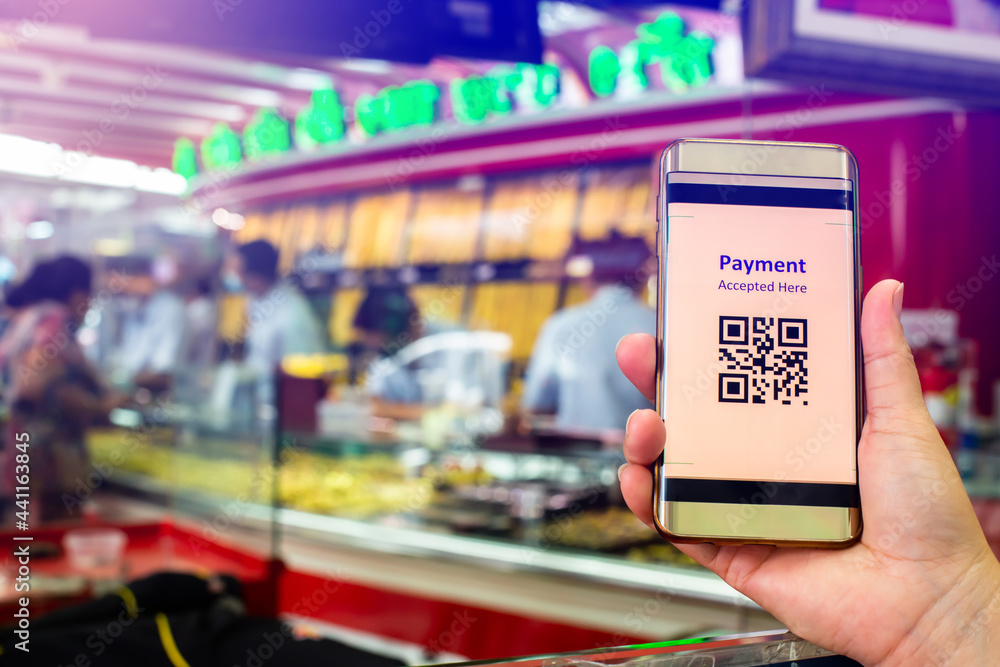 Selective focus to QR Code tag on smart phone in hand of customer with blurry gold jewelry shop to accepted generate digital pay without money. Qr code payment concept.