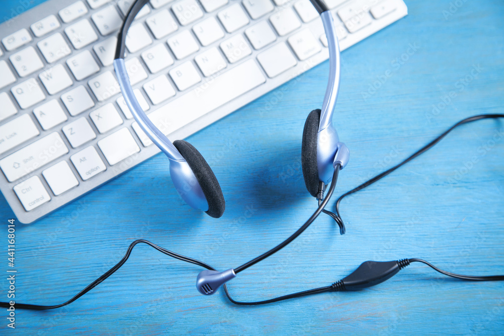 Customer service headset and computer keyboard on the blue background. Customer service headset and computer keyboard on the blue background.