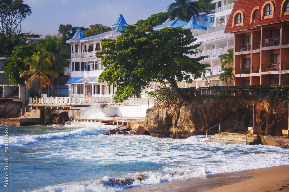 wave breaks about the pier on the coast of the Atlantic Ocean and the colonial architecture of the Caribbean islands