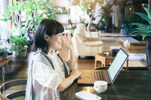 暖かい雰囲気の空間で、ノートパソコンの画面を見る女性