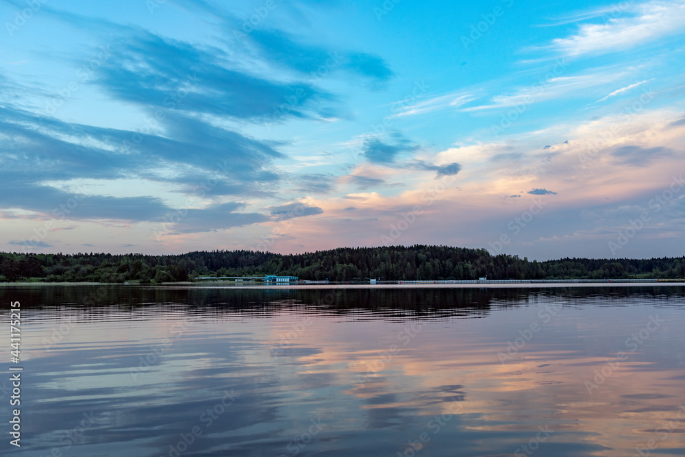 Evening landscape with a lake and clouds. Clouds are reflected in the water.