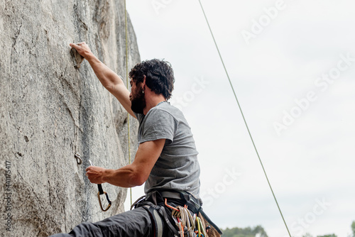 Foto young boy anchoring himself with hooks to the rock during a day of climbing in the mountains